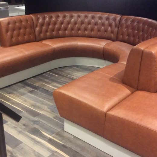 Custom curved banquette seating with bench, wood veneer privacy screen and cantilevered work surface for casino