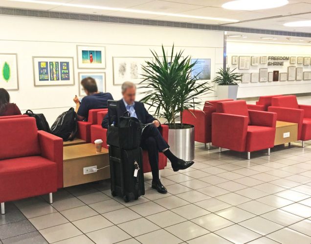 travelers reading and recharging in airport terminal lounge seating