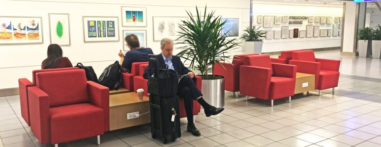 travelers reading and recharging in airport terminal lounge seating