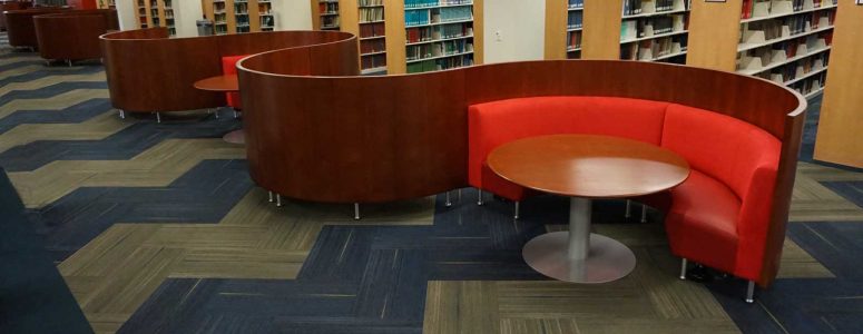 Serpentine curved banquettes with wood veneer privacy screens and matching tables in University Library