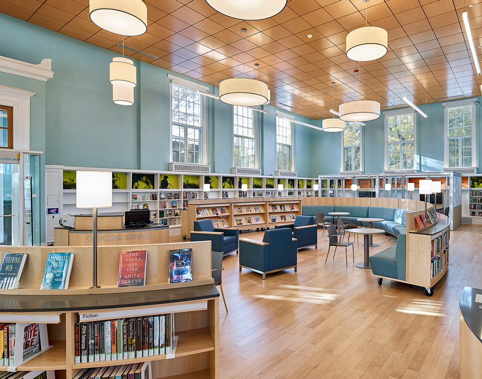 curved library shelving with integrated library seating, book displays and mobile service desk