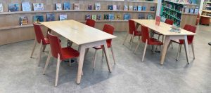 Library chairs with wood seat and back stained red around wood table