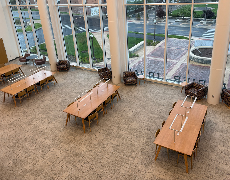 Overhead view of light-wood AGATI Etta group study tables beside tall windows at JMU Carrier Library.