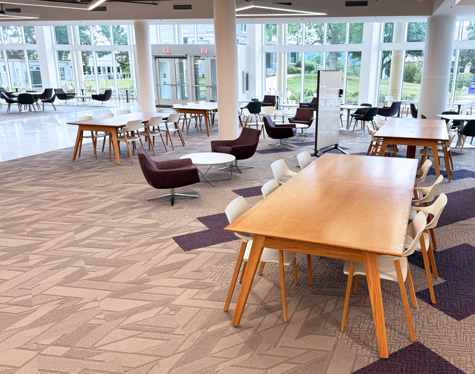 Light-wood AGATI Etta study tables and lounge seating in JMU Carrier Library’s bright, window-lined entrance