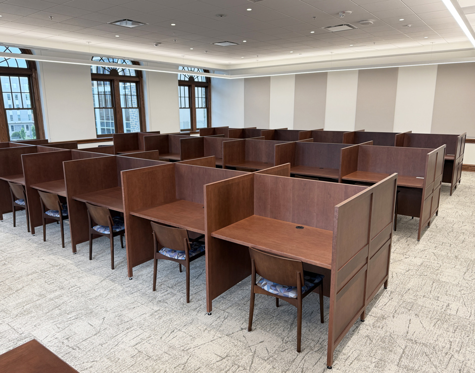 Rows of dark-wood AGATI Williams study carrels beside tall windows at JMU Carrier Library.