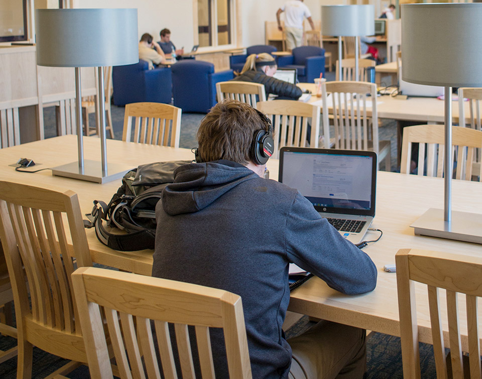 wood library furniture in a busy library space featuring study tables, built in lighting and power